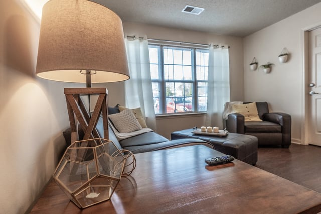 Table lamp sofa armchair and ottoman living room at Revelry Flats at Milledgeville in Milledgeville Student Accommodation