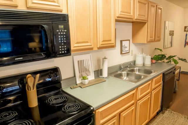 Black microwave above stove double sink cabinetry kitchen at Grove at Cheney in Pullman Student Accommodation