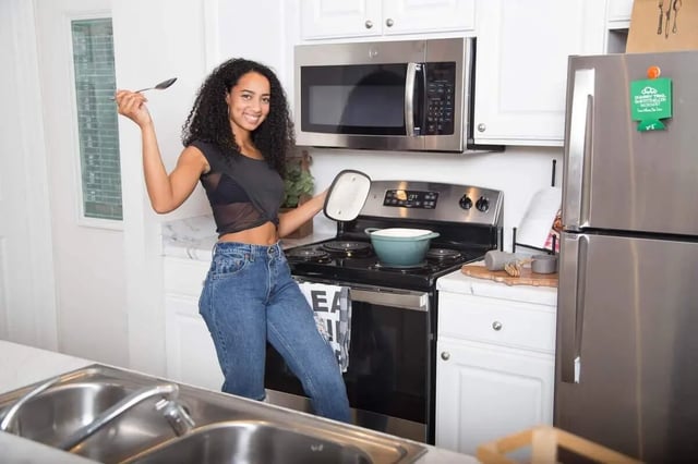 Woman holding spoon pot on stove kitchen at Quarry Trail in Knoxville Student Accommodation