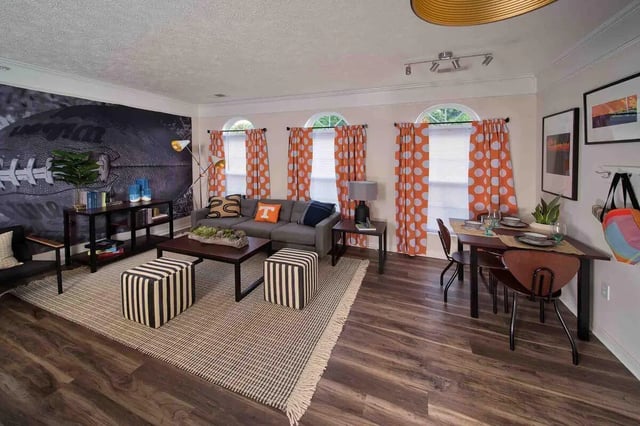 Gray sofa with orange accent pillow and football wall living room at Quarry Trail in Knoxville Student Accommodation