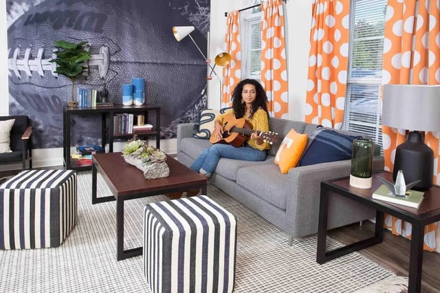 Woman playing guitar on sofa with striped ottomans living room at Quarry Trail in Knoxville Student Accommodation