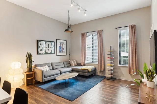 Gray sectional sofa wood coffee table blue rug living room at Paloma at University City in Philadelphia Student Accommodation