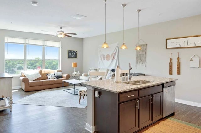 Kitchen island with sink and living room living room at Midtown Stillwater in Stillwater Student Accommodation