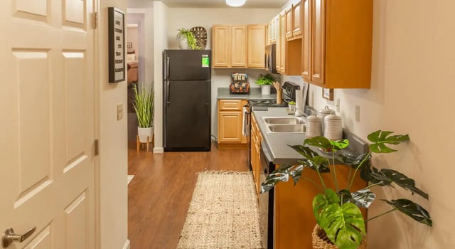 Black refrigerator wood cabinets double sink rug kitchen at The Grove at Cheney in Cheney Student Accommodation
