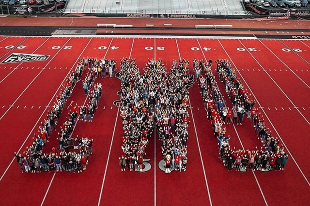 Large group of people forming letters on football field exterior at The Grove at Cheney in Cheney Student Accommodation