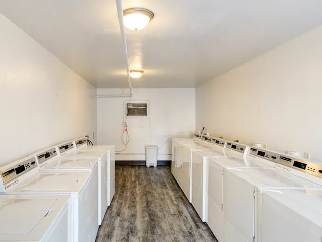Washers and dryers on wood floor laundry room at Vivo | Toledo in Toledo Student Accommodation