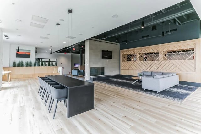Communal dining table grey sofa fireplace lounge area at Current Midtown in Williamsburg Student Accommodation