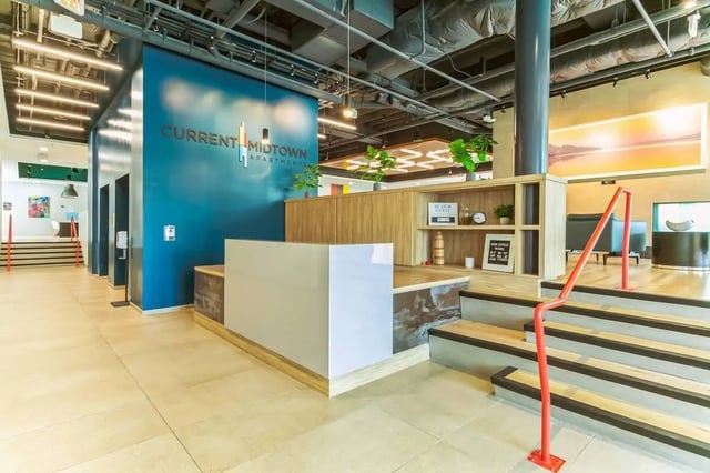 Reception desk with modern shelving and stairs Lobby at Current Midtown in Williamsburg Student Accommodation