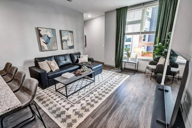 Black leather sectional sofa and patterned rug living room at Junction 49 in Charlotte Student Accommodation