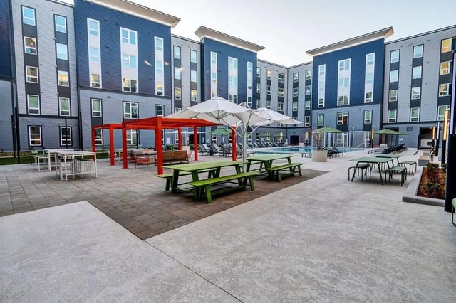 Picnic tables lounge chairs pool and apartment buildings exterior at Junction 49 in Charlotte Student Accommodation