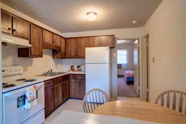 Kitchen with white appliances wood cabinets and dining table kitchen at Grand Duke in Harrisonburg Student Accommodation