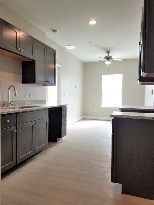 Dark cabinets sink granite countertop and open living kitchen at Peak of Boone in Boone Student Accommodation