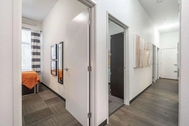 Bedroom with orange bedding and mirrored art hallway. at Arena District in Eugene Student Accommodation