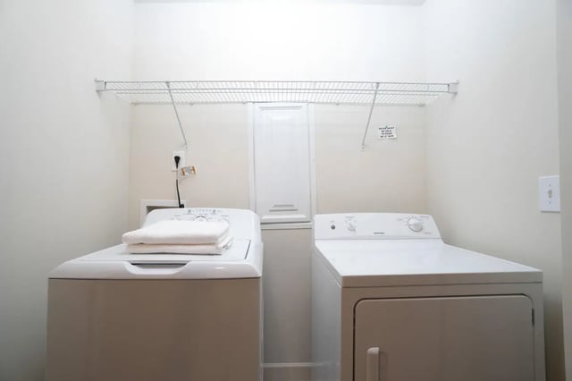 Washer dryer unit with folded towels laundry room at Copper Beech Townhomes - Harrisonburg in Harrisonburg Student Accommodation