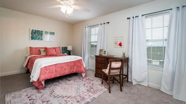 Bed with pink covers and wooden desk Bedroom at Copper Beech Townhomes - Harrisonburg in Harrisonburg Student Accommodation