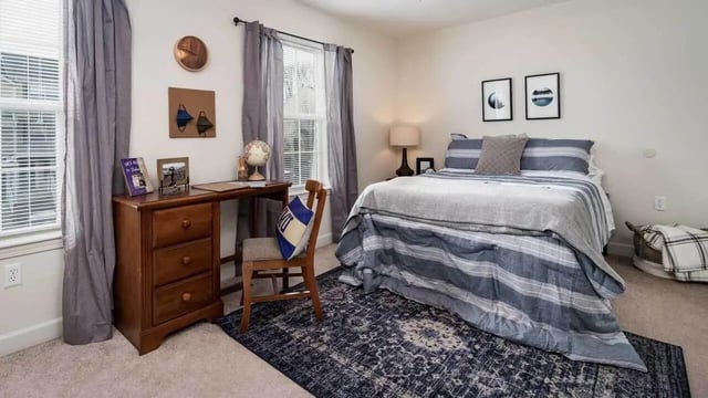 Bed desk chair rug and artwork bedroom at Copper Beech Townhomes - Harrisonburg in Harrisonburg Student Accommodation