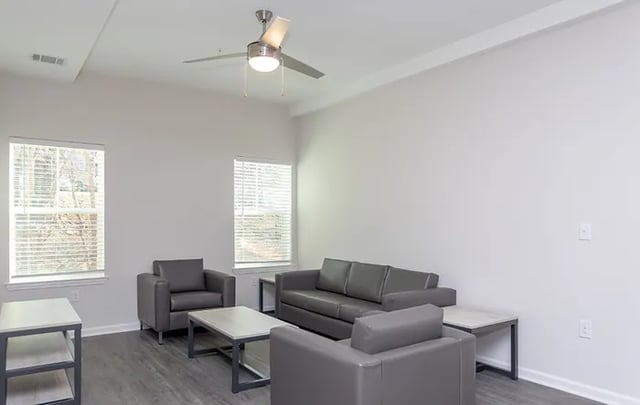 Gray sofas armchairs coffee tables ceiling fan living room at Rivers Walk in Boone Student Accommodation