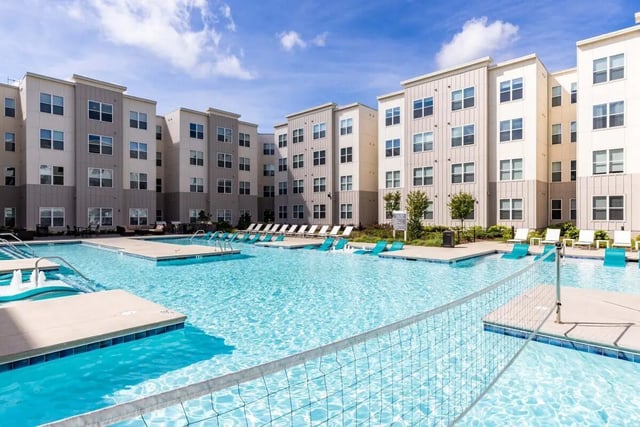 Swimming pool with volleyball net and lounge chairs exterior at Rush Charlotte in Charlotte Student Accommodation