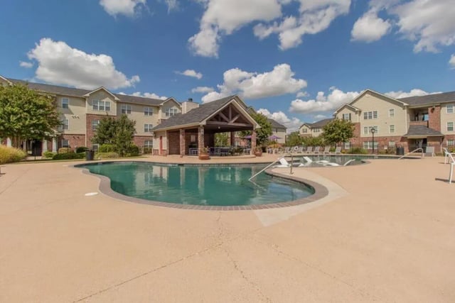 Pool with lounge chairs and covered patio exterior at Grove at Stephenville in Stephenville Student Accommodation