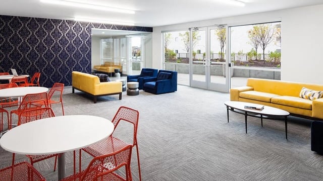 Yellow sofa blue chairs white tables lounge area at Latitude Lincoln in Lincoln Student Accommodation