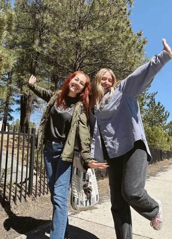 Two smiling young women with arms raised exterior at Table Rock in Flagstaff Student Accommodation
