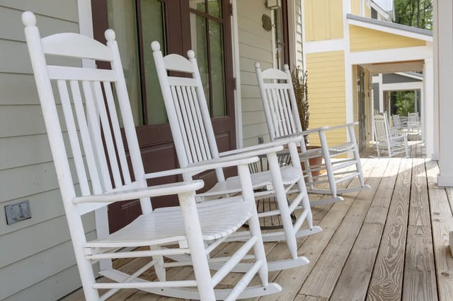 White rocking chairs on wooden porch exterior at Traditions Oxford Apartments in Oxford Student Accommodation
