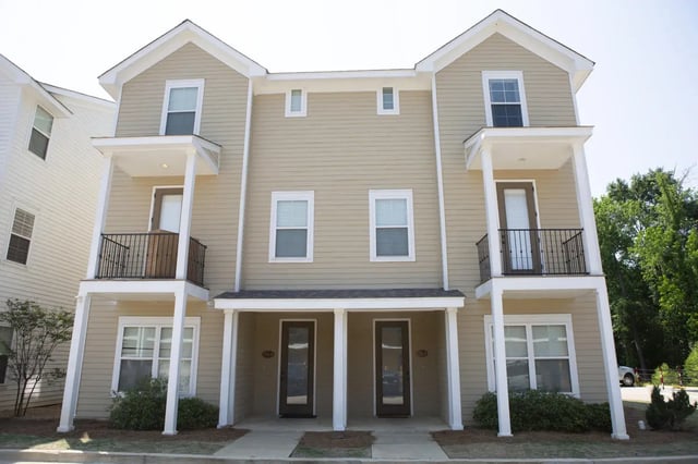 Tawny townhomes with balconies and doorways exterior at Village Walk Oxford Apartments in Oxford Student Accommodation