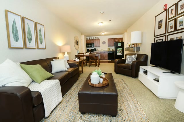 Leather sofa ottoman chairs television kitchen living room at The Verge at Grand Forks in Grand Forks Student Accommodation
