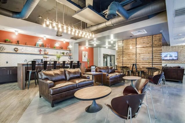 Leather couches tables bar stools kitchen lounge at 12 North in College Station Student Accommodation