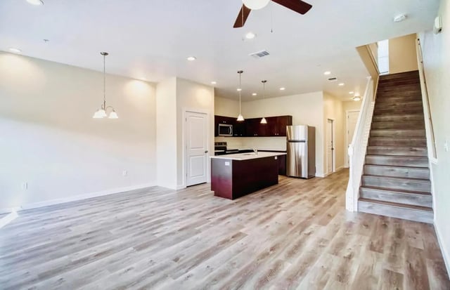 Kitchen island refrigerator stairs living area at BelCara Luxury Townhomes in San Antonio Student Accommodation