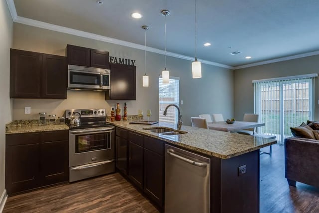 Dark cabinets microwave stove sink dishwasher dining table kitchen at BelCara Luxury Townhomes in San Antonio Student Accommodation