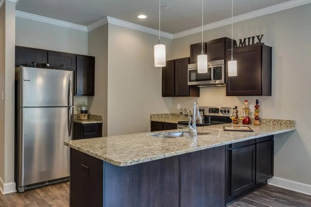 Stainless refrigerator dark cabinets granite island kitchen at BelCara Luxury Townhomes in San Antonio Student Accommodation