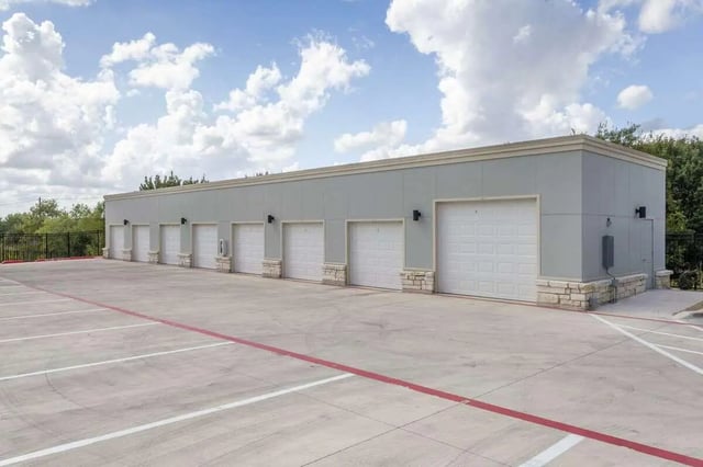 Multiple white garage doors with stone accents Exterior at Bridge at Cameron in Austin Student Accommodation