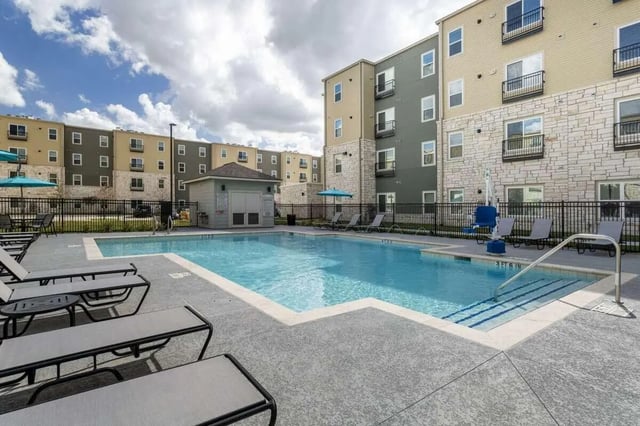 Swimming pool with lounge chairs and apartment buildings Exterior at Bridge at Cameron in Austin Student Accommodation