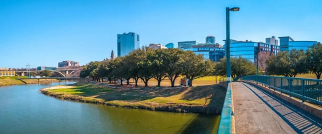 Waterfront park with trees and city skyline exterior at Bryan Flats in Fort Worth Student Accommodation