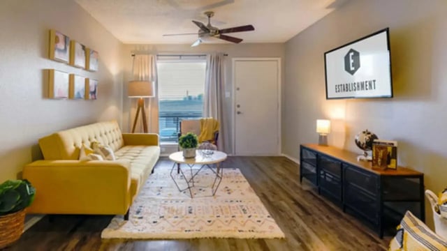 Yellow couch rug coffee table artwork TV living room at Establishment in Austin Student Accommodation
