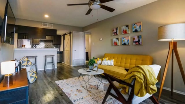 Yellow couch coffee table artwork kitchen bar living room at Establishment in Austin Student Accommodation