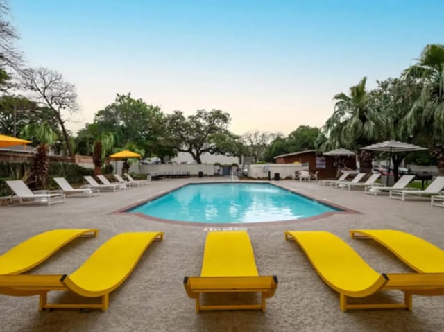 Pool with yellow lounge chairs and umbrellas exterior at Establishment in Austin Student Accommodation