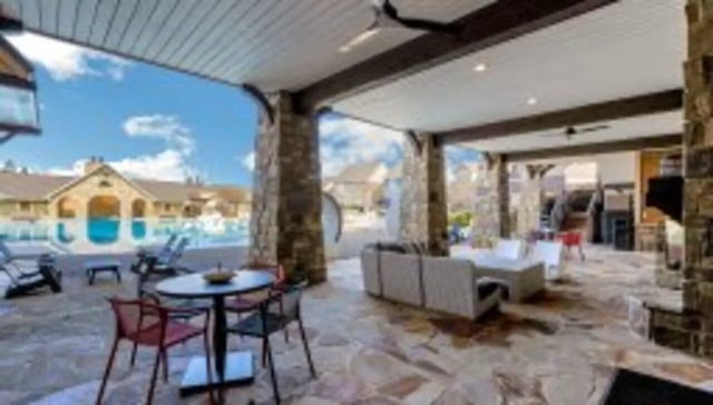 Outdoor lounge with sofas tables chairs and pool exterior at The Cottages at Lake Tamaha in Tuscaloosa Student Accommodation