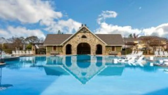Large pool with lounging chairs and building exterior at The Cottages at Lake Tamaha in Tuscaloosa Student Accommodation