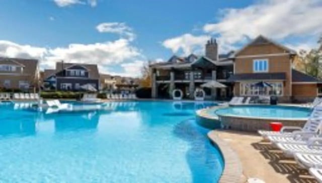 Poolside lounging chairs with apartment buildings exterior at The Cottages at Lake Tamaha in Tuscaloosa Student Accommodation