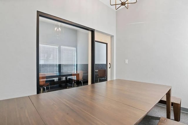 Large wooden table chairs through glass conference room at Central House on Stadium in Mobile Student Accommodation