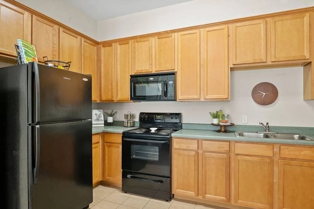 Black refrigerator stove microwave wood cabinets kitchen at Central House on Stadium in Mobile Student Accommodation
