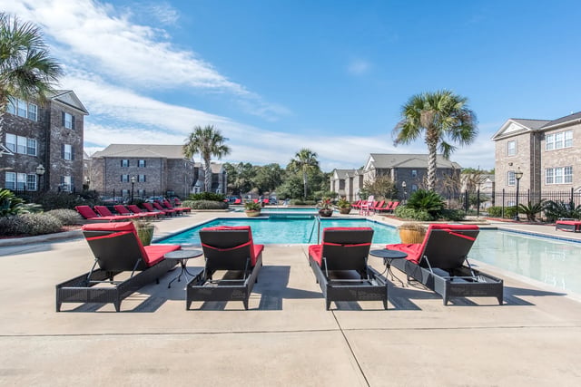 Red lounge chairs by swimming pool exterior at Central House on Stadium in Mobile Student Accommodation