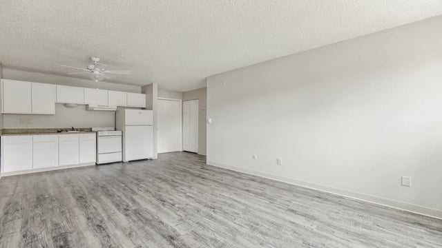 White cabinets stove refrigerator fan living area kitchen at Wind River Place Apartments in Colorado Springs Student Accommodation