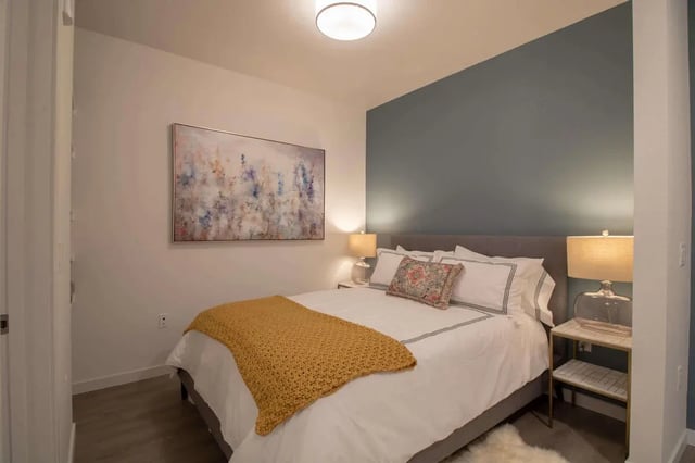 Bed with yellow throw painting and bedside lamp bedroom at 1515 Flats in Denver Student Accommodation