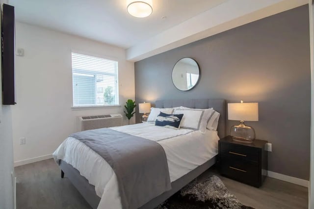 Bed with grey blanket white sheets beside table Bedroom at 1515 Flats in Denver Student Accommodation