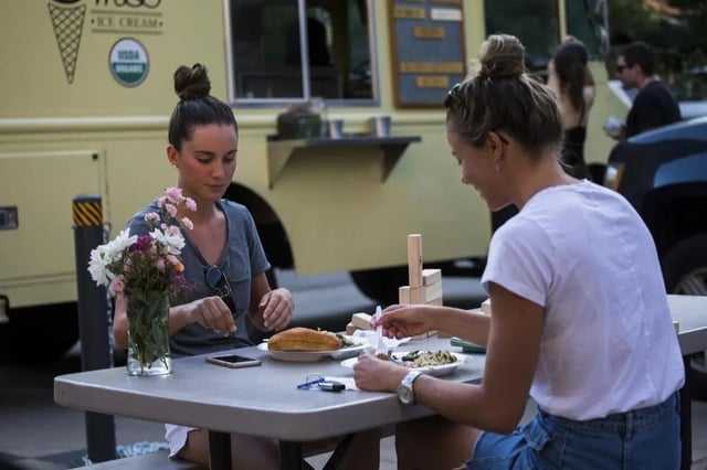 Students eating at a picnic table outdoor dining at Uptown Broadway in Boulder Student Accommodation