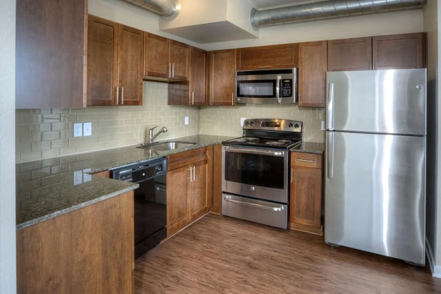 Stainless steel appliances wood cabinets granite countertops kitchen at Uptown Broadway in Boulder Student Accommodation