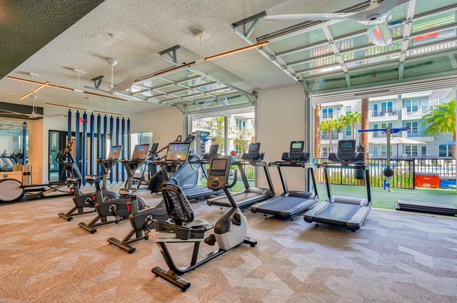 Treadmills and exercise bikes workout space living room at Alsander GNV in Gainesville Student Accommodation